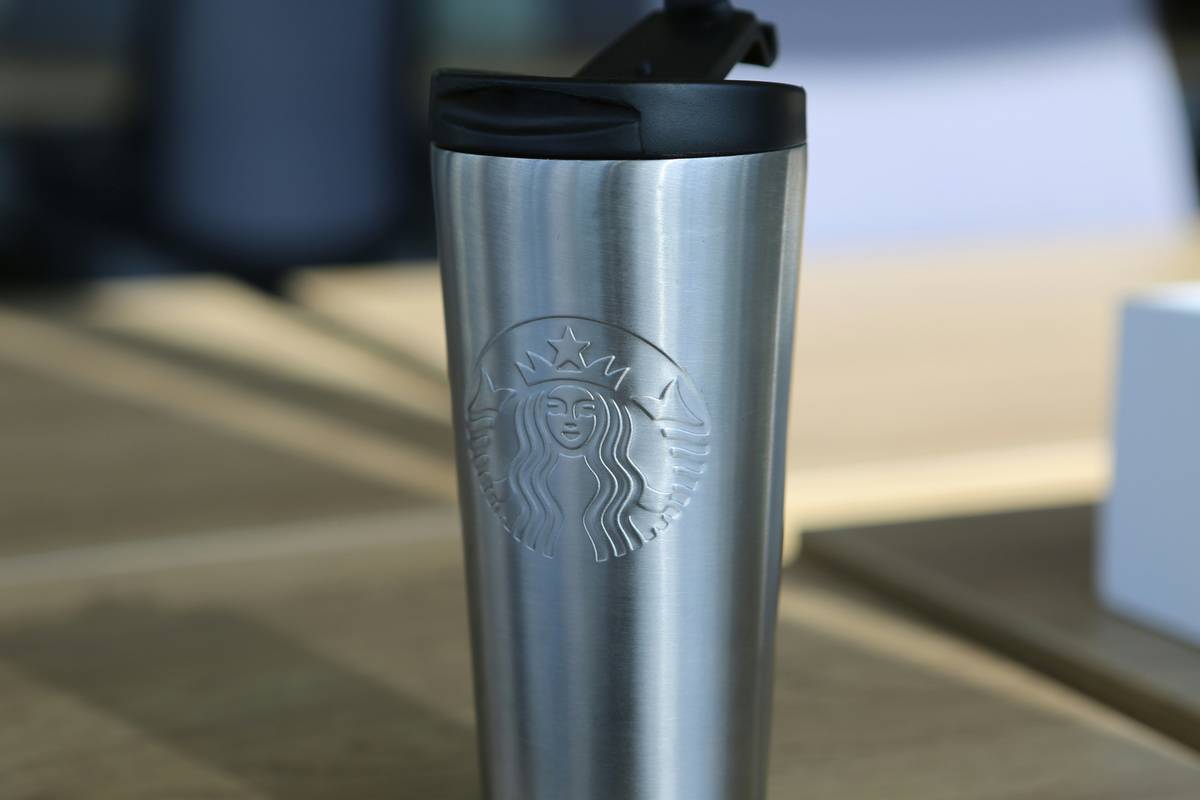 eco friendly reusable coffee cups with silicone lids on a wooden countertop