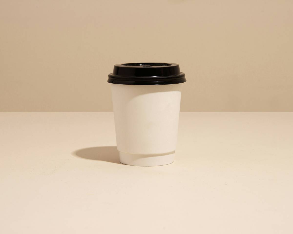 Assortment of reusable plastic coffee cups with lids on a kitchen counter, showcasing different lid mechanisms and colors