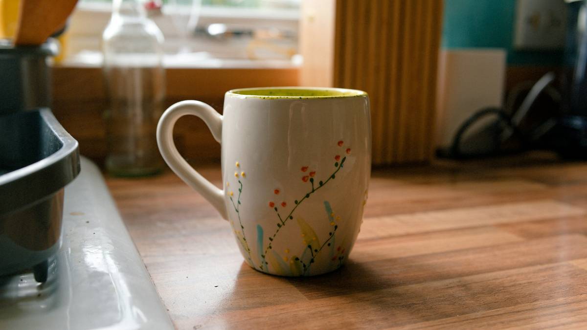 eco friendly option reusable cup lid on a stainless steel tumbler with morning coffee and bamboo coaster