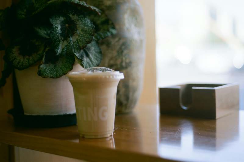 Two diverse hands holding different reusable cups with lids on a recycled paper background