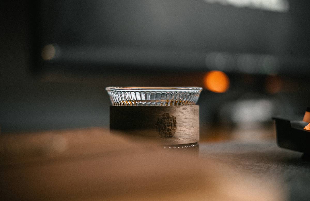 Clear insulated cups with lids on a wooden kitchen counter next to citrus fruits and a reusable straw